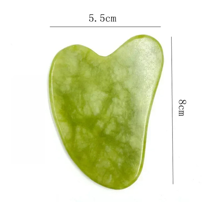 Pedra gua sha verde de jade, formato coração, medidas 5,5 cm por 8 cm, fundo branco.