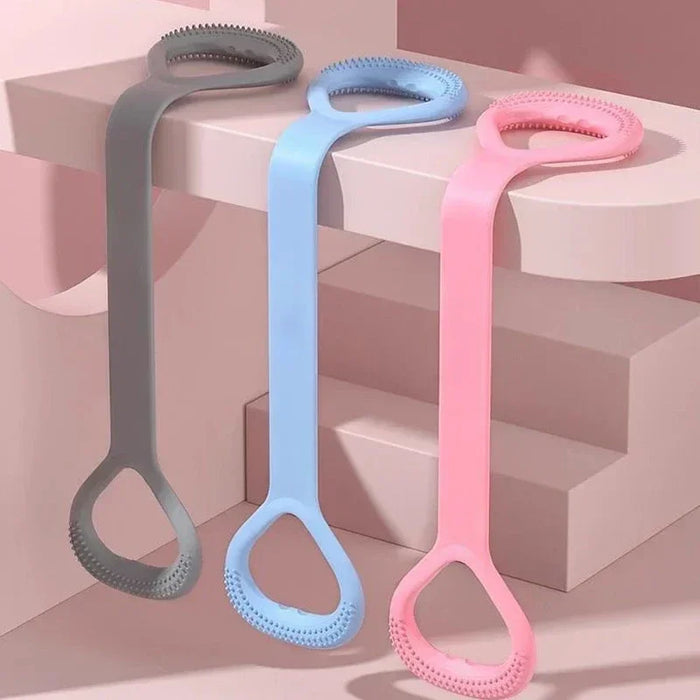Esfoliador de silicone cinza, azul e rosa pendurados em ambiente minimalista rosa.